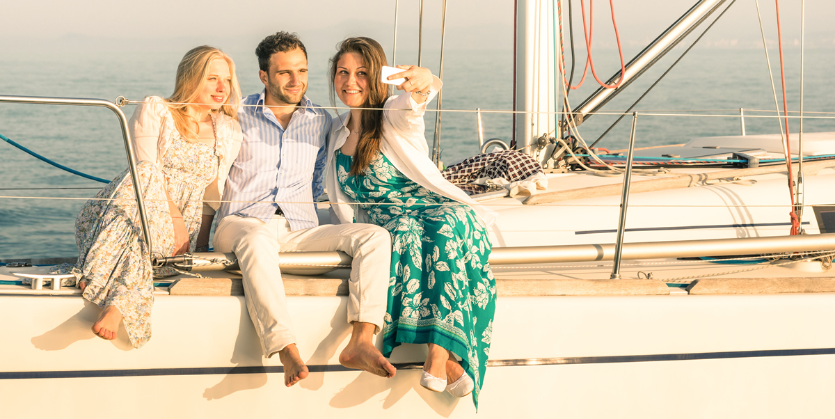 Three Atractive People Sitting on Sailboat Enjoying a Beautiful Sunny Day